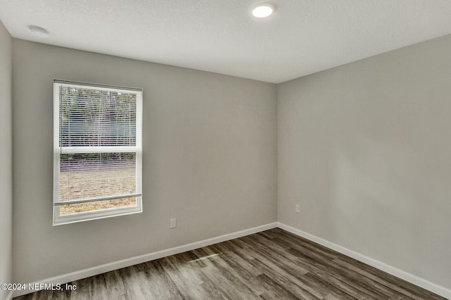 unfurnished room featuring a healthy amount of sunlight, a textured ceiling, baseboards, and wood finished floors