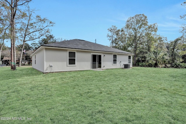 back of property featuring cooling unit and a lawn