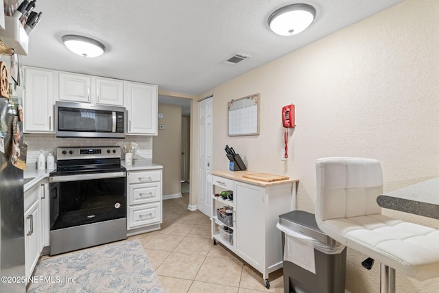 8880 Old Kings Rd S Unit 21, Jacksonville, FL 32257 - kitchen with light tile patterned floors, visible vents, decorative backsplash, white cabinets, and appliances with stainless steel finishes