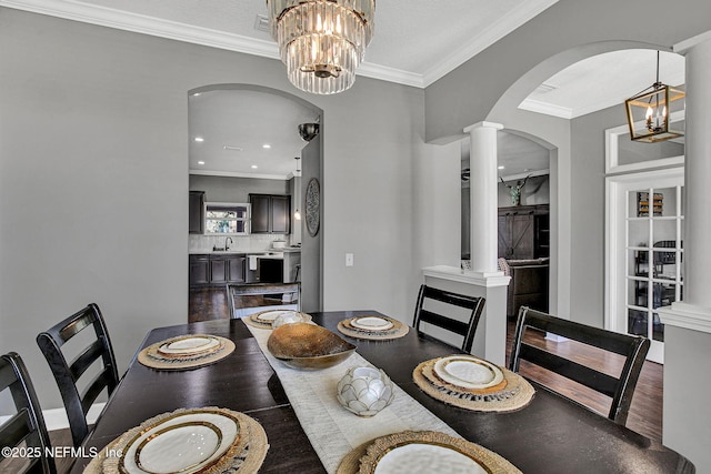 dining space with arched walkways, a chandelier, crown molding, and ornate columns