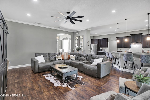 living area with visible vents, dark wood-style floors, arched walkways, and ceiling fan