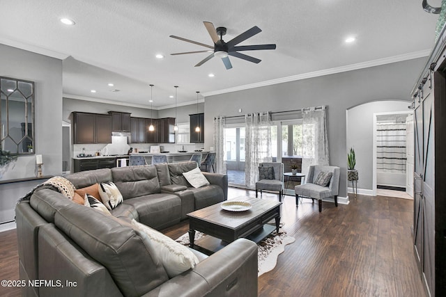 living area with dark wood-style floors, arched walkways, baseboards, and ceiling fan