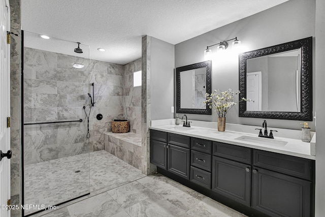 full bath featuring a sink, a textured ceiling, marble finish floor, and a tile shower