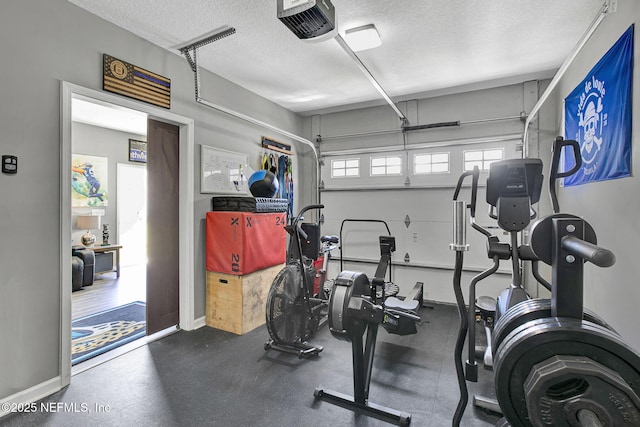 workout area featuring baseboards, a textured ceiling, and a garage