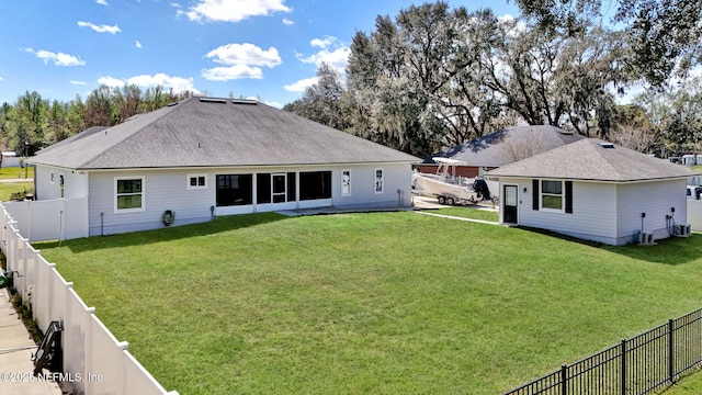 rear view of house with a fenced backyard, a lawn, and roof with shingles