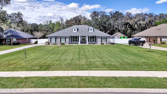 view of front of home with brick siding, a front yard, and fence