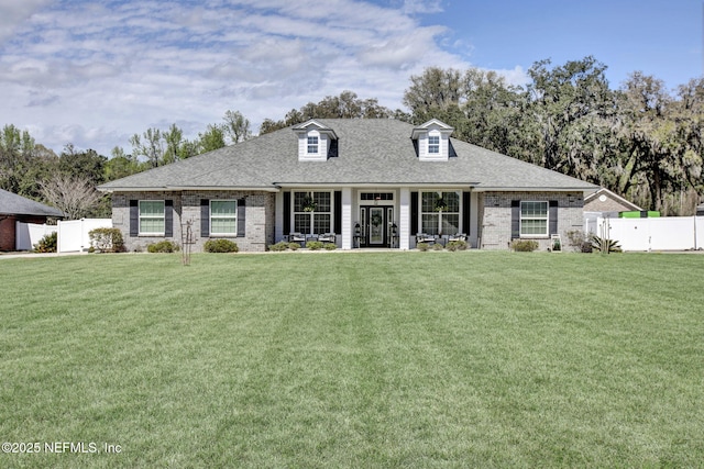 view of front facade with a front yard, fence, and roof with shingles