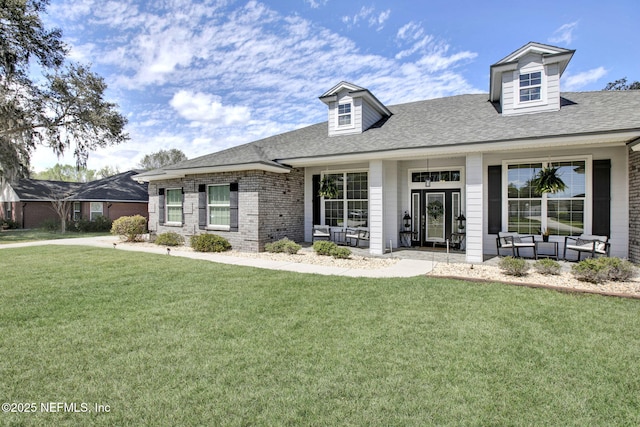 cape cod-style house with a front yard, covered porch, brick siding, and a shingled roof