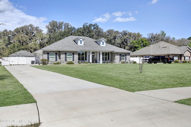 view of front of property with concrete driveway, a gate, fence, and a front lawn