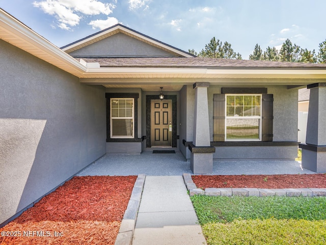 doorway to property featuring stucco siding and covered porch