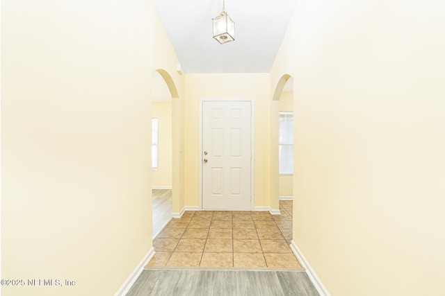 interior space with light tile patterned floors, baseboards, and arched walkways