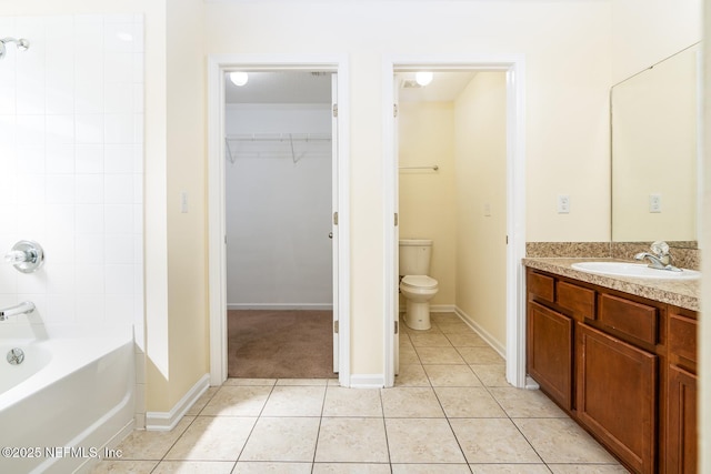 full bathroom featuring tile patterned floors, a walk in closet, toilet, baseboards, and vanity