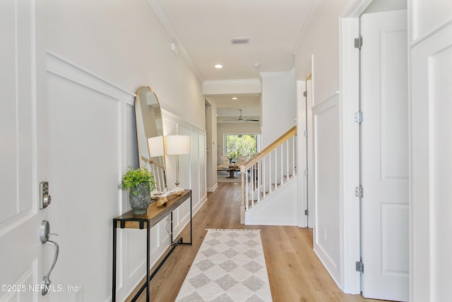 entryway with ceiling fan, light wood-style floors, ornamental molding, and stairs