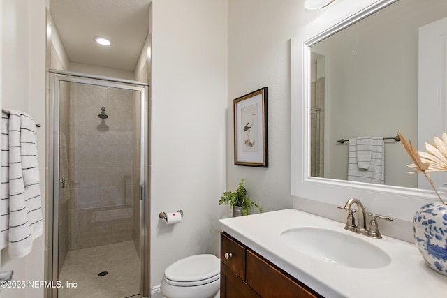 full bathroom featuring vanity, a shower stall, and toilet