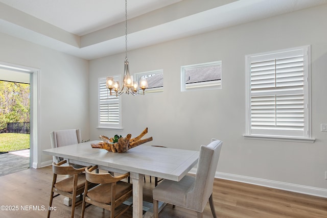 dining room featuring light wood-style flooring, baseboards, and an inviting chandelier