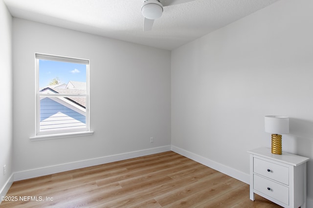 unfurnished room featuring baseboards, a textured ceiling, light wood-style flooring, and a ceiling fan