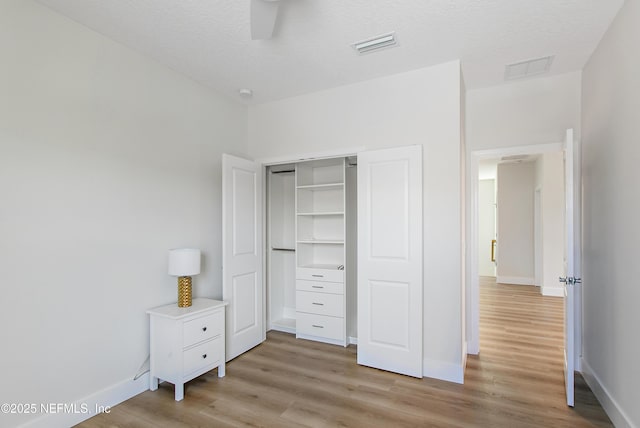 unfurnished bedroom featuring light wood-style flooring, baseboards, visible vents, and a closet