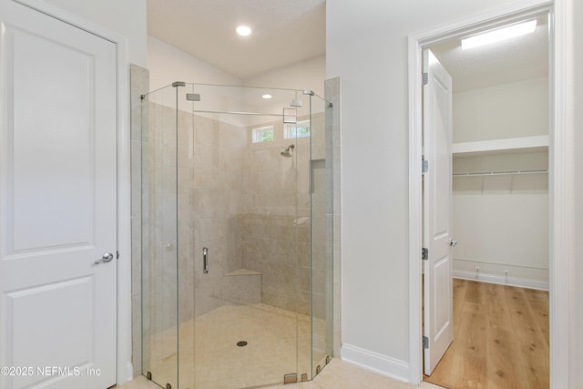 bathroom with baseboards, wood finished floors, a stall shower, and a spacious closet