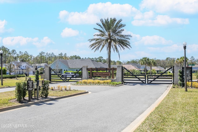 view of street featuring a gate, curbs, street lights, a gated entry, and a residential view