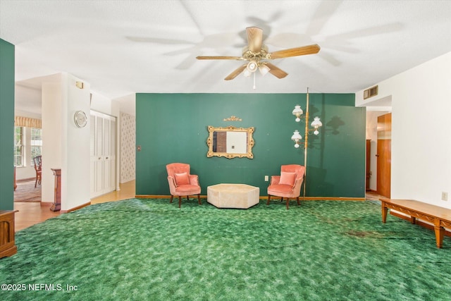 living area featuring visible vents, carpet floors, baseboards, and ceiling fan