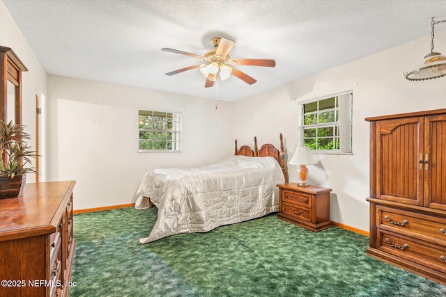 bedroom with multiple windows, a textured ceiling, baseboards, and dark colored carpet