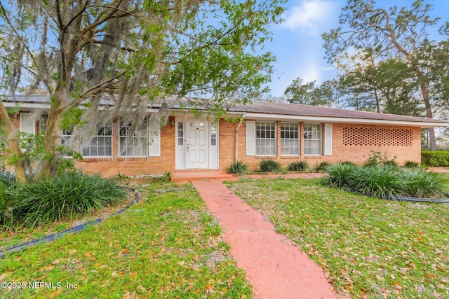 single story home featuring metal roof, brick siding, and a front yard