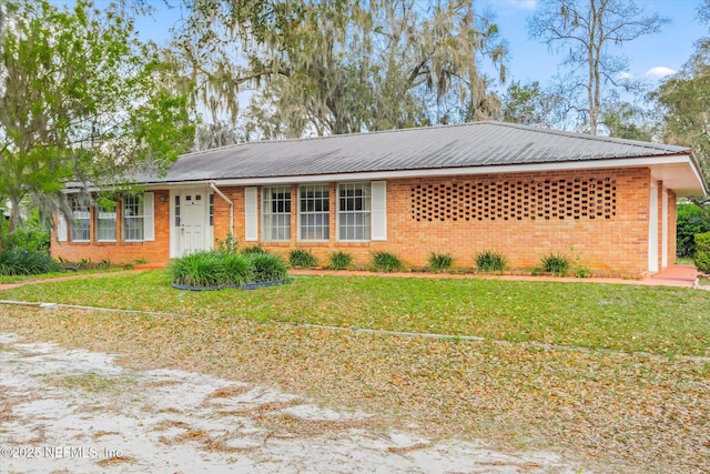 ranch-style home with brick siding, metal roof, and a front lawn