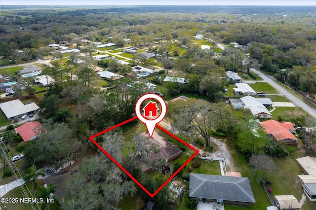 drone / aerial view featuring a wooded view and a residential view