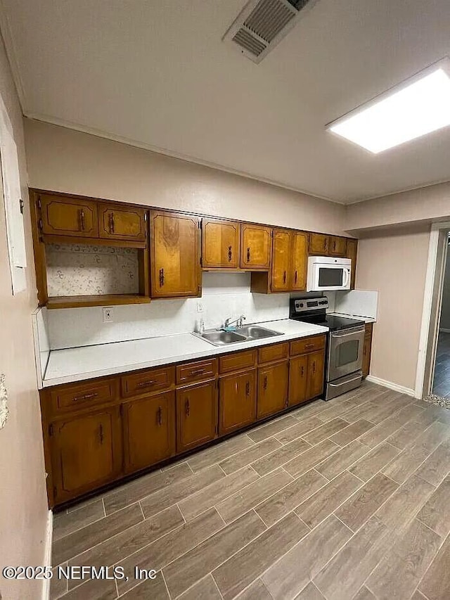 kitchen featuring white microwave, visible vents, light countertops, electric stove, and a sink