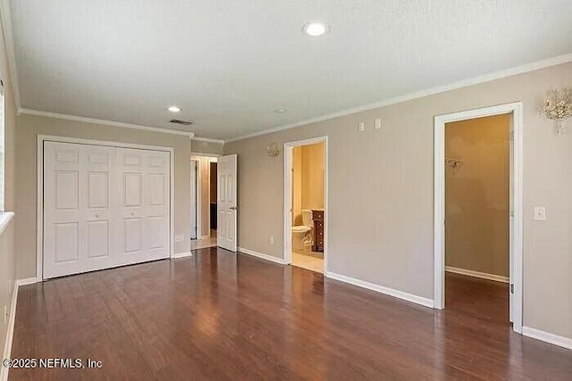 unfurnished bedroom featuring a spacious closet, baseboards, ornamental molding, wood finished floors, and a closet