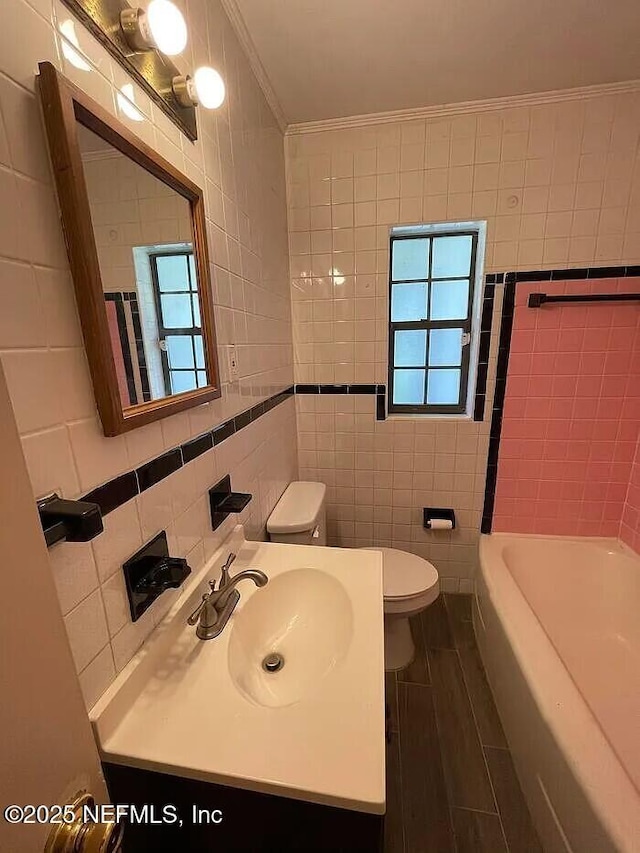 full bathroom featuring toilet, tile walls, ornamental molding, and a washtub