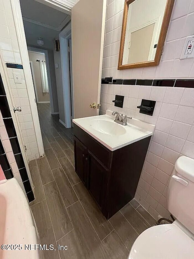 bathroom with wood tiled floor, toilet, tile walls, and vanity