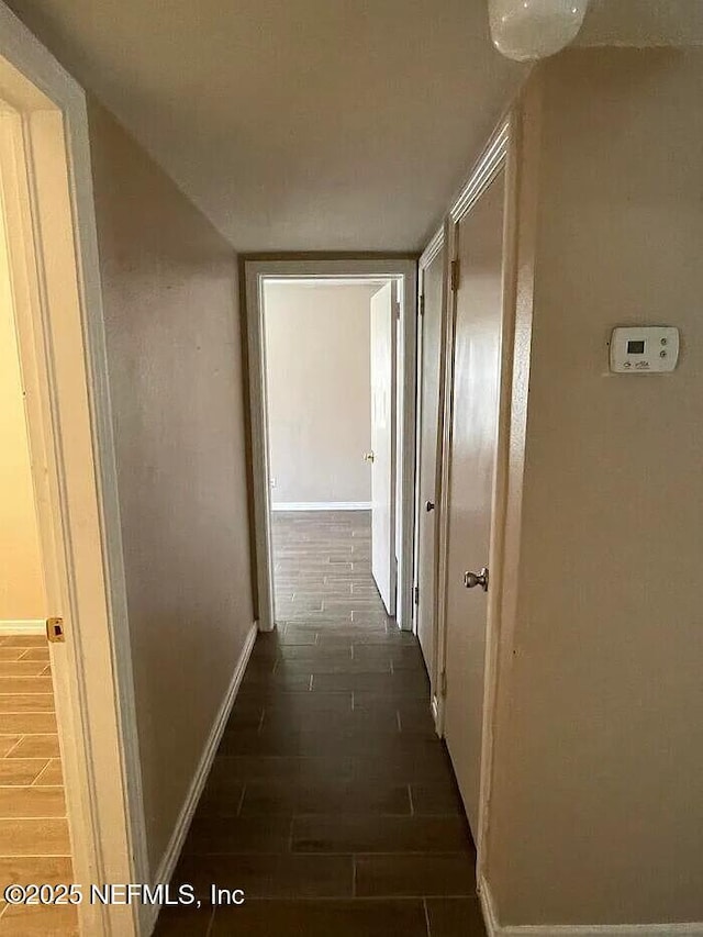 hall featuring baseboards and wood tiled floor