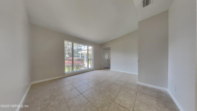 spare room featuring light tile patterned floors, visible vents, baseboards, and lofted ceiling