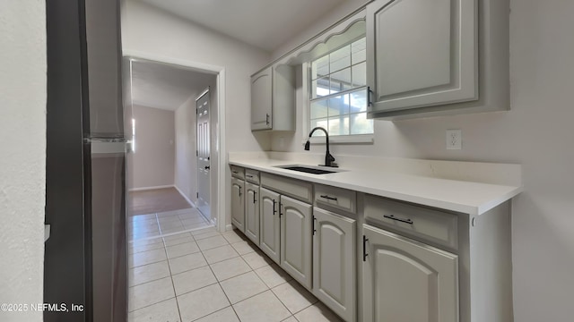 kitchen featuring a sink, light tile patterned flooring, gray cabinets, and light countertops