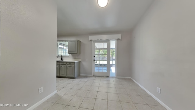 interior space featuring light tile patterned floors, baseboards, and a sink