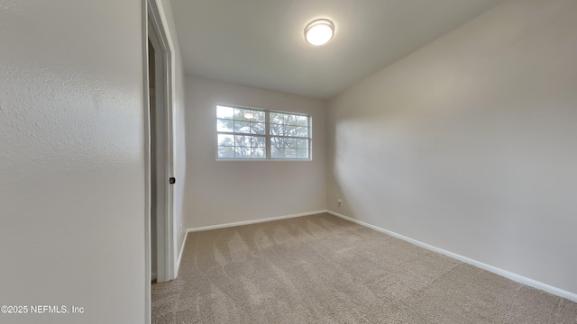 carpeted empty room featuring baseboards