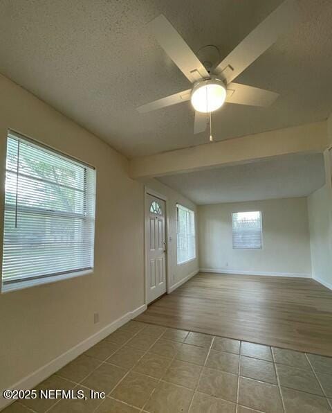 foyer entrance featuring baseboards, a textured ceiling, ceiling fan, and tile patterned flooring