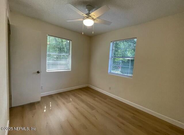 unfurnished room with a textured ceiling, baseboards, and wood finished floors