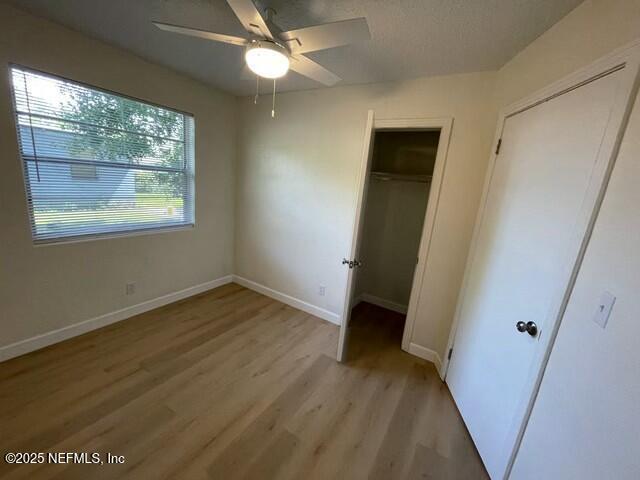 unfurnished bedroom featuring a ceiling fan, light wood-type flooring, and baseboards