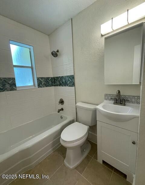 full bathroom featuring toilet, tile patterned flooring, bathtub / shower combination, vanity, and a textured wall