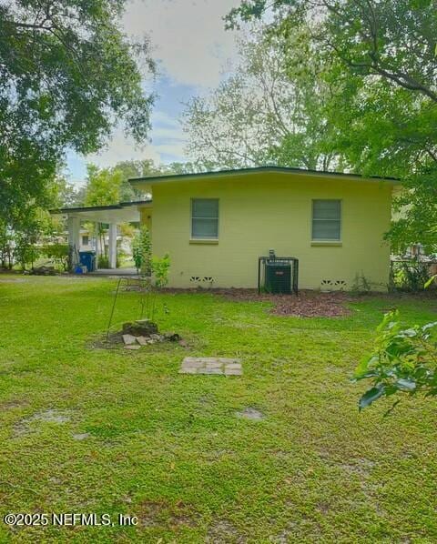 rear view of property with central AC unit and a lawn