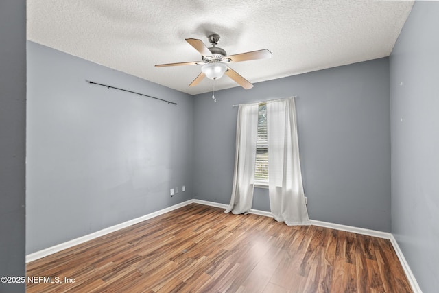 empty room featuring a textured ceiling, baseboards, a ceiling fan, and wood finished floors