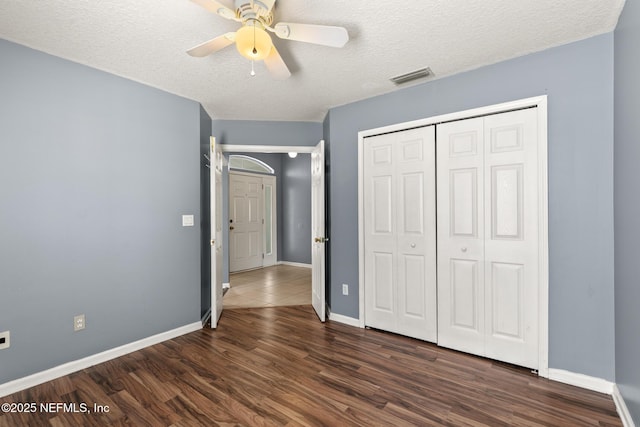 unfurnished bedroom with baseboards, dark wood-style floors, visible vents, and a textured ceiling