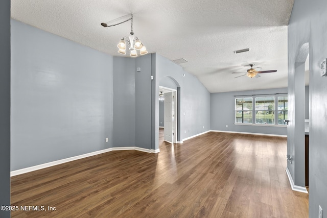 spare room featuring ceiling fan with notable chandelier, a textured ceiling, wood finished floors, arched walkways, and baseboards