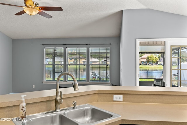 kitchen featuring a sink, a textured ceiling, ceiling fan, and vaulted ceiling