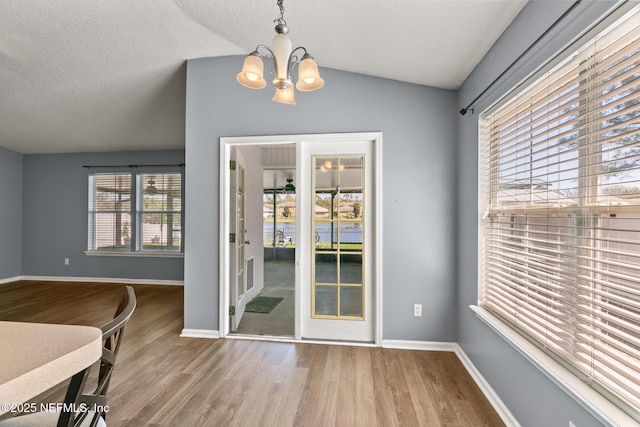 dining area featuring baseboards, lofted ceiling, an inviting chandelier, and wood finished floors