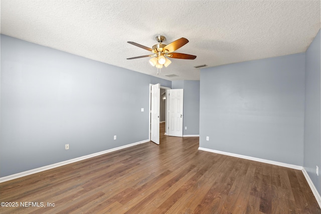 empty room featuring a ceiling fan, wood finished floors, visible vents, and baseboards