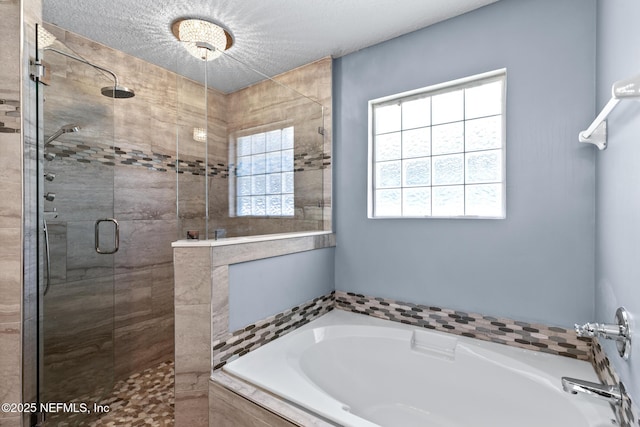 bathroom featuring a shower stall, a garden tub, a healthy amount of sunlight, and a textured ceiling