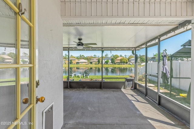 unfurnished sunroom featuring a water view and a ceiling fan